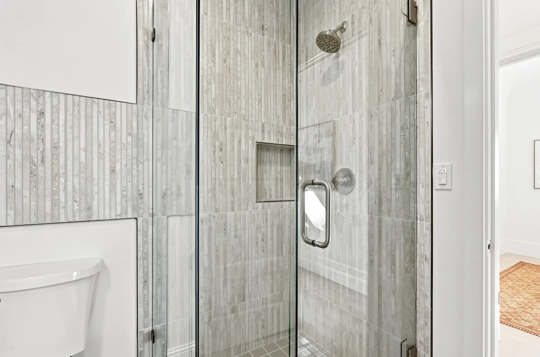 Shower detail: vertical porcelain, a recessed niche and a curbless threshold.