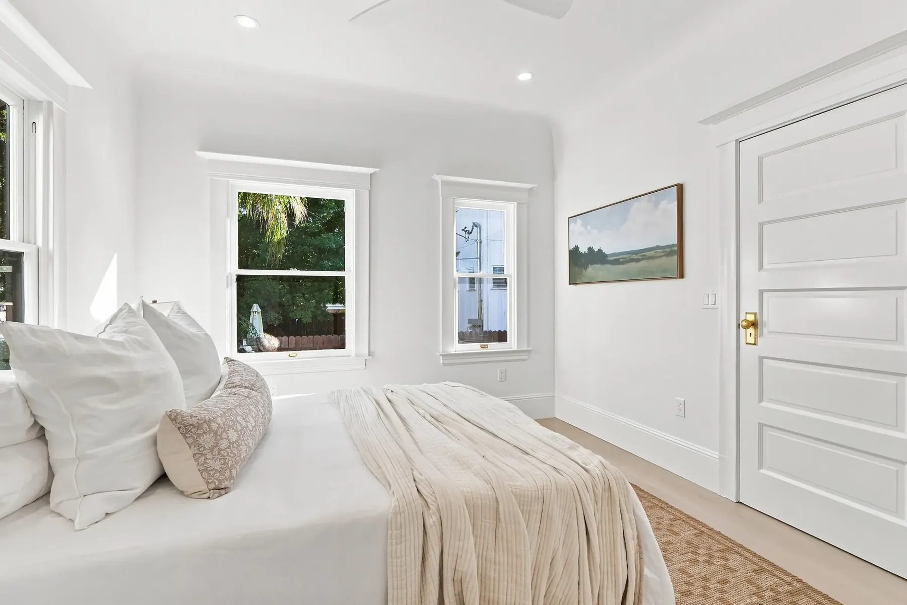 Primary bedroom with the original window casing retained and a new solid-core door.