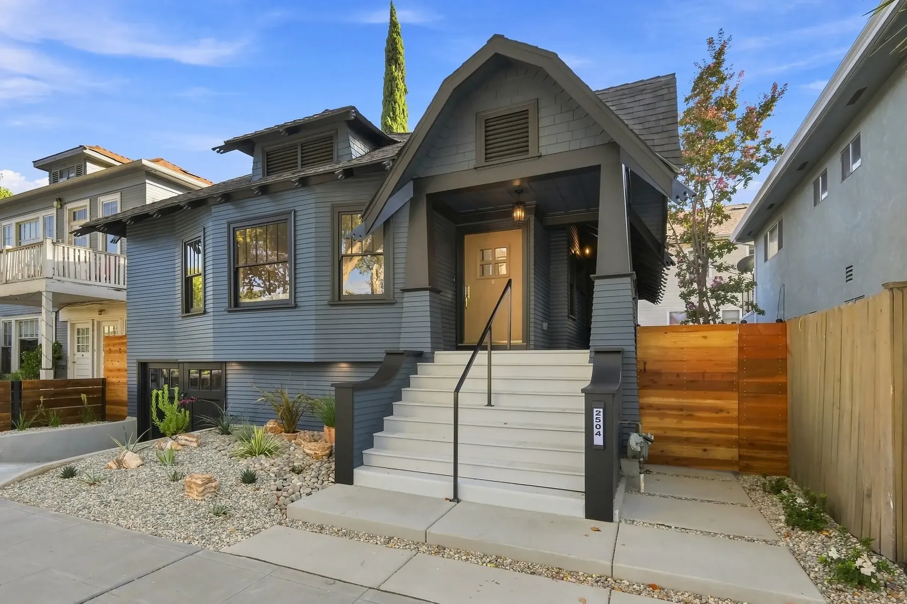 Raised entry with a new concrete stair and steel rail. Drought-appropriate planting replaced lawn across the full front yard.