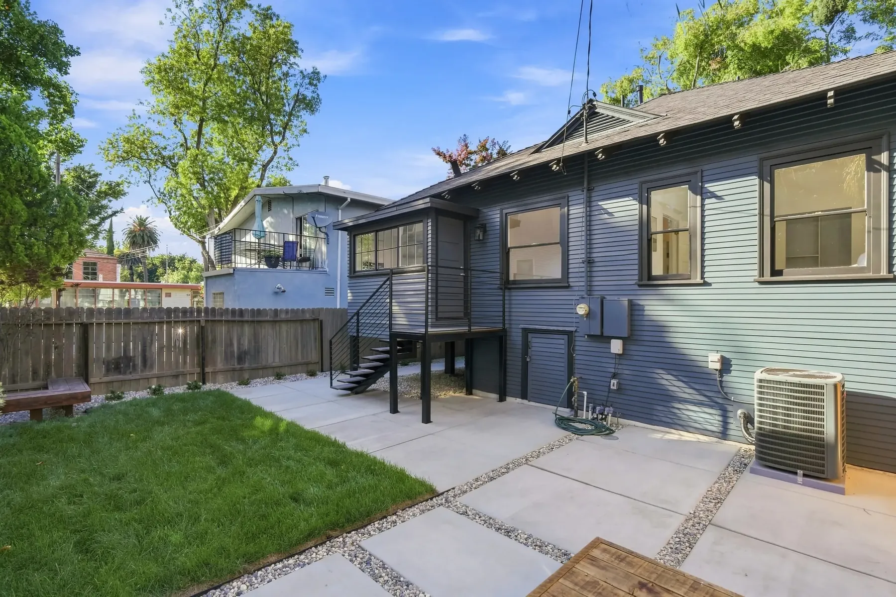 Rear elevation. New siding, new rear stair, and lawn re-established across the full yard.