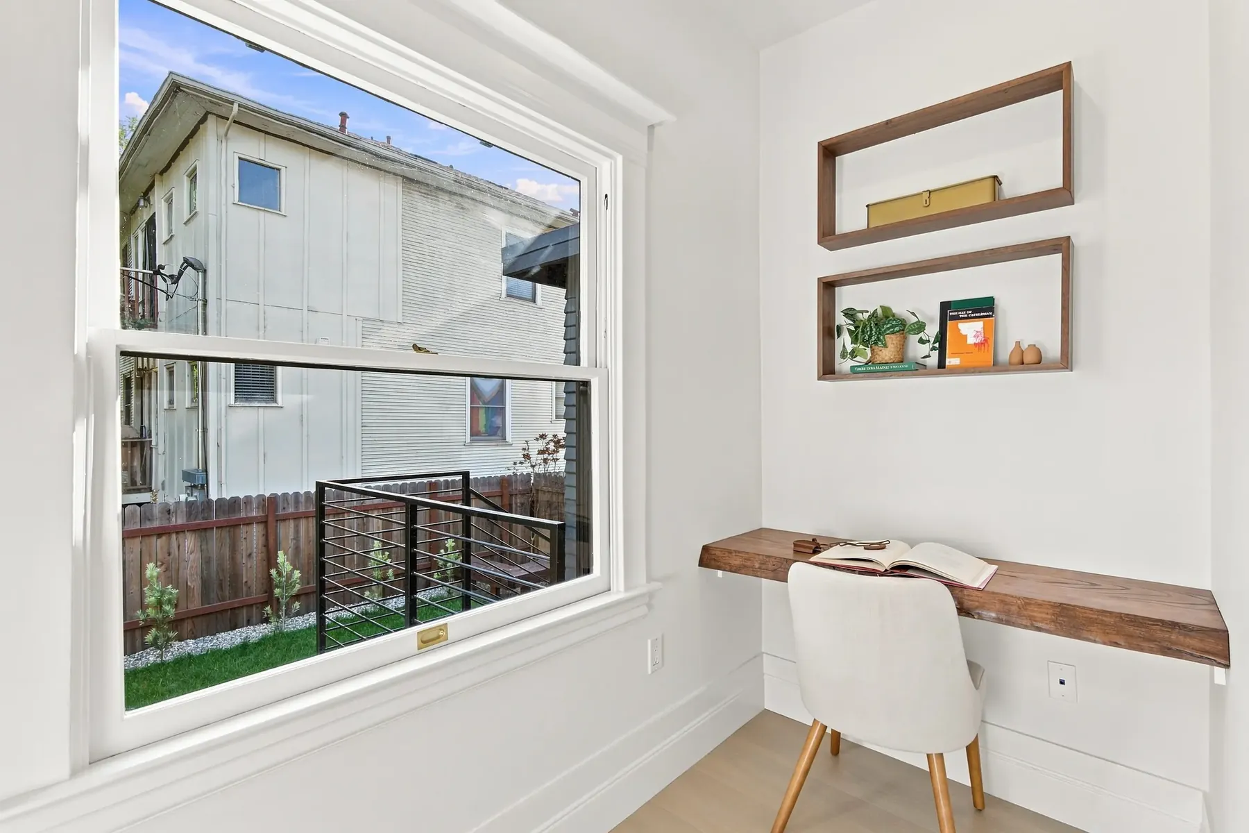 A work nook built into a secondary room, with a new picture window and floating white-oak shelves.