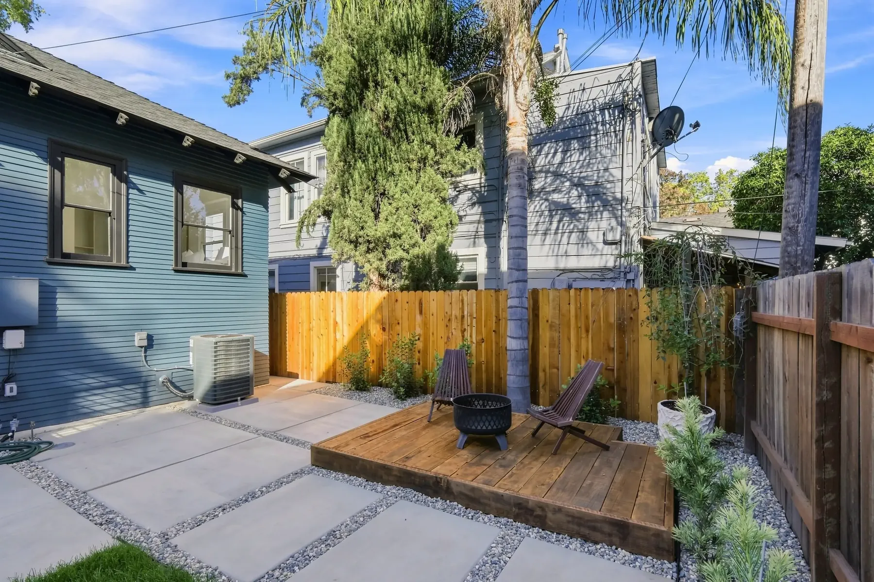 Deck and fire-pit seating tucked against the fence line at the side of the house.