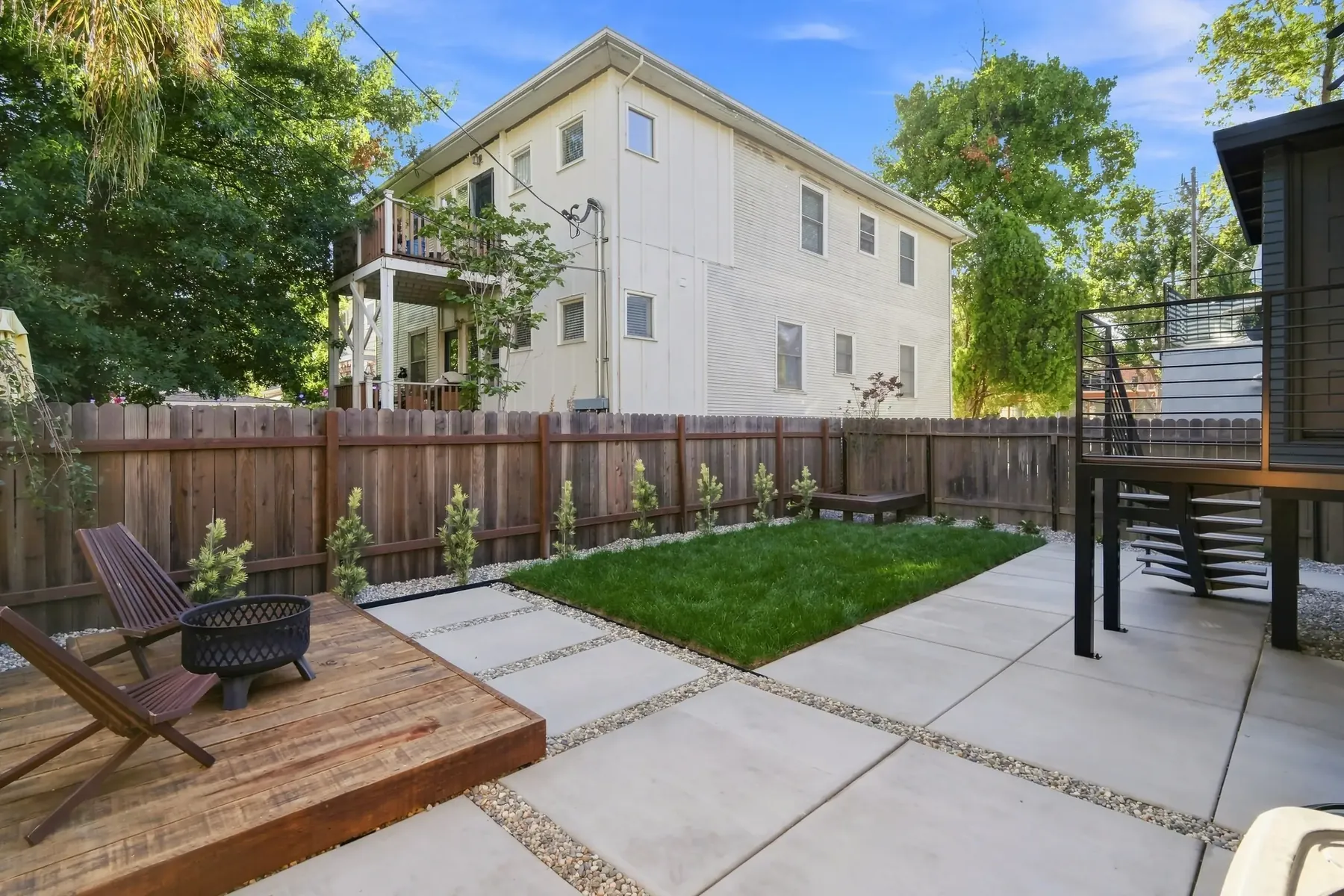 Rear yard with a new deck, steel stair and concrete pads set in gravel joints.